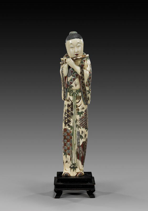 ANTIQUE POLYCHROMED IVORY FIGURE: ANTIQUE POLYCHROMED IVORY FIGUREUnusual and antique, Japanese carved and polychromed marine (walrus) ivory figure: of a flutist playing while standing in finely decorated robes; Circa 1900; H: 10 7/8"