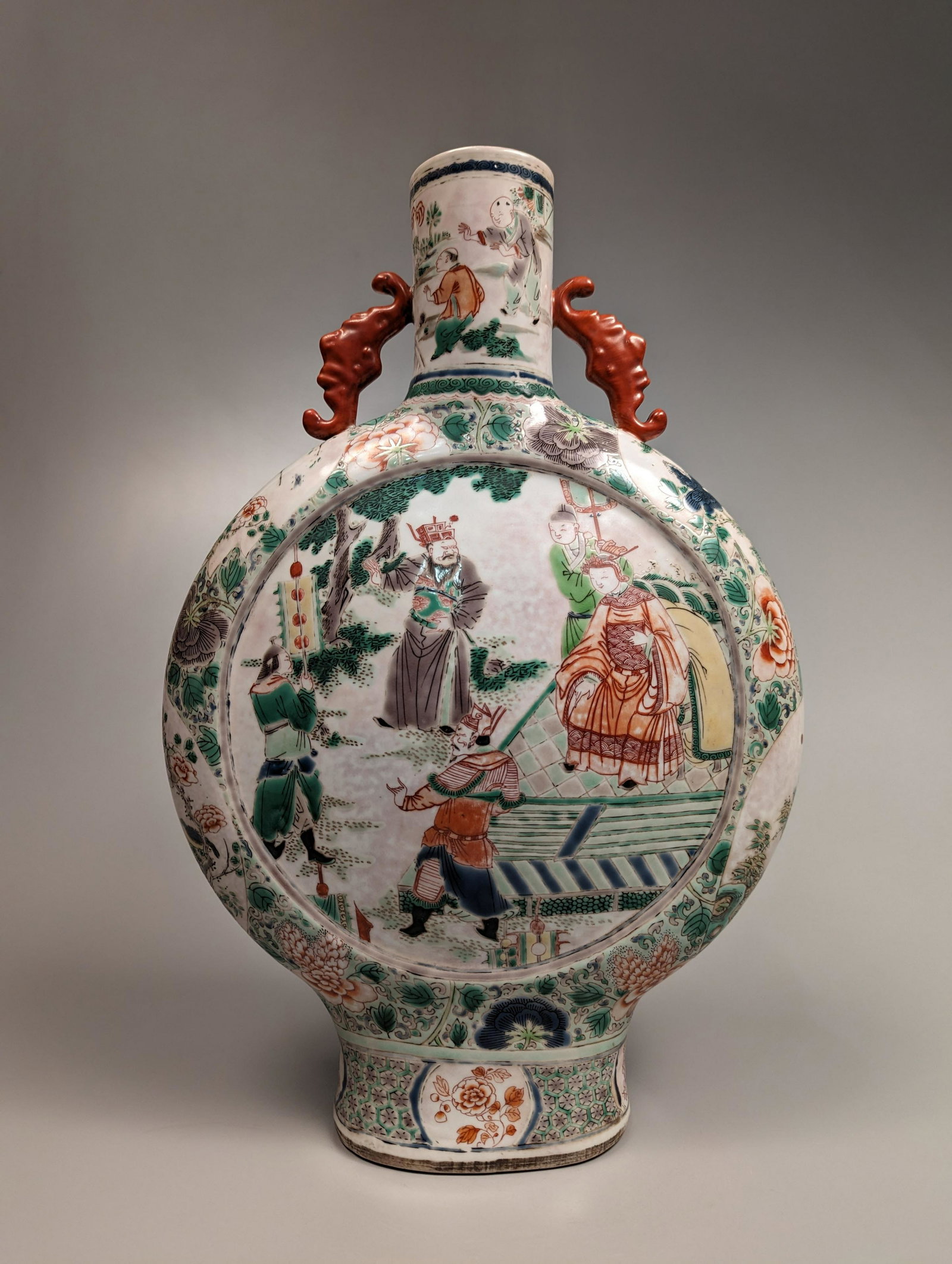 Kangxi-Style Famille Verte Porcelain Moon Flask: Chinese Kangxi-style Famille Verte enameled porcelain moon flask; the front and verso each depicting a court scene, one in the garden and another in a study; flanked by scattered florals along the rou
