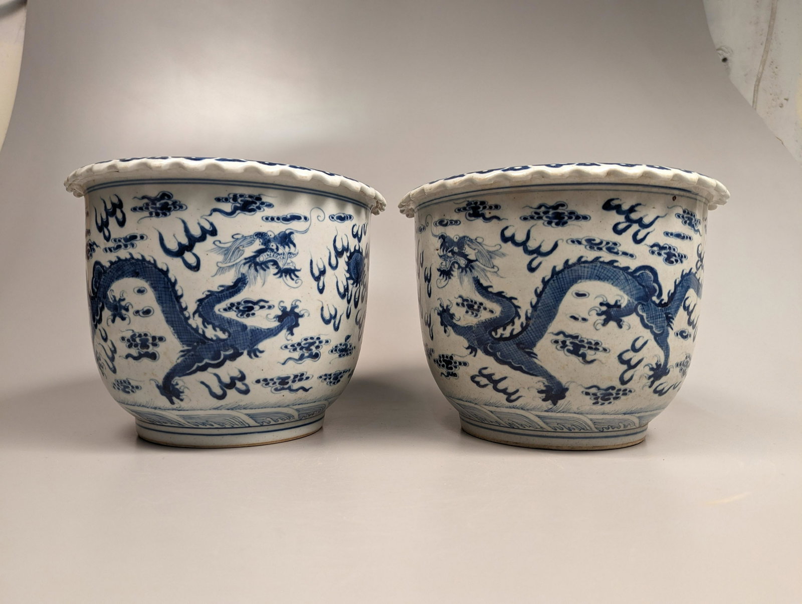 Pair Wanli-Style Blue and White Porcelain Flower Pots: Pair of Chinese Wanli-style, underglazed blue and white porcelain flower pots; each nicely detailed with design of a pair of imperial five-clawed dragons flanking a flaming pearl, amid wispy clouds; w