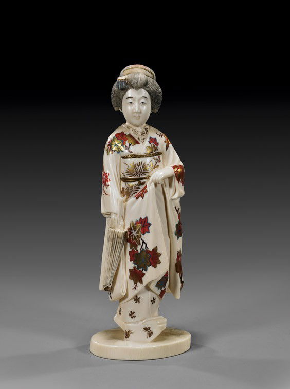 JAPANESE POLYCHROMED IVORY OKIMONO: JAPANESE POLYCHROMED IVORY OKIMONODelicately polychrome lacquered, early 20th Century Japanese ivory okimono; of a traditional beauty dressed in an ornate kimono decorated with maple leaves, and holdi