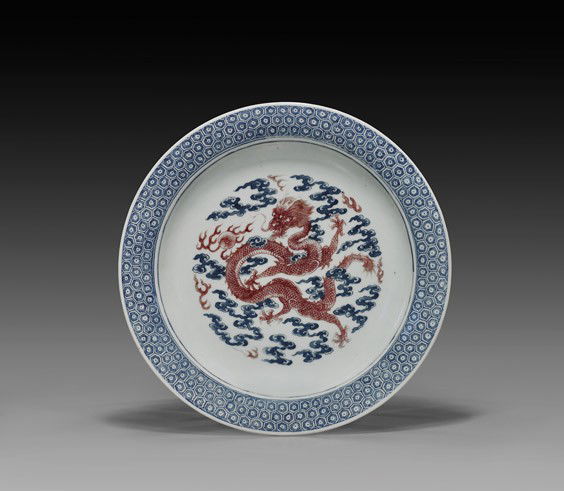 ANTIQUE UNDERGLAZE RED DRAGON DISH: ANTIQUE UNDERGLAZE RED DRAGON DISHAntique Chinese porcelain dragon dish; centering a copper red five-clawed dragon amid underglazed blue clouds, framed by a honeycomb patterned blue band to the everte