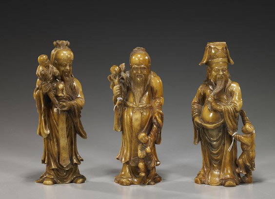 Group of Three Carved Soapstone Star Gods: Group of Three Carved Soapstone Star Gods Unusual group of 3, Chinese carved soapstone Star Gods: each with a child, one with a branch of peaches, another gripping his belt and beard; each of yellowis