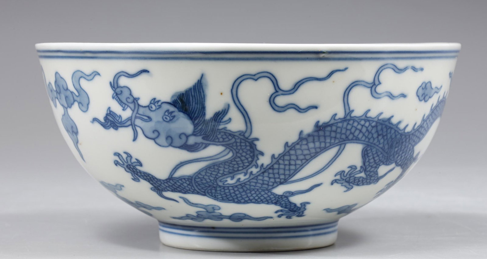 Chinese Blue & White Porcelain Dragon Bowl: Chinese blue and white porcelain bowl; the interior with central writing and five clawed dragon within double concentric rings; the exterior depicting two five clawed dragons chasing the flaming pearl