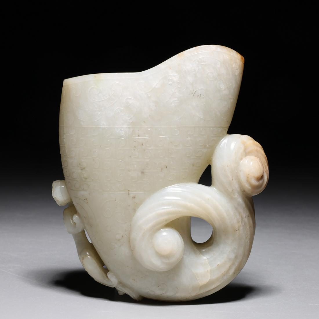 Chinese Qing Dynasty Rhyton Cup: Finely carved Chinese mutton fat jade rhyton cup of typical form with decoration of coiled qiulong clamoring up the outer edge, the body with incised archaic designs of geometric patterns in low relie