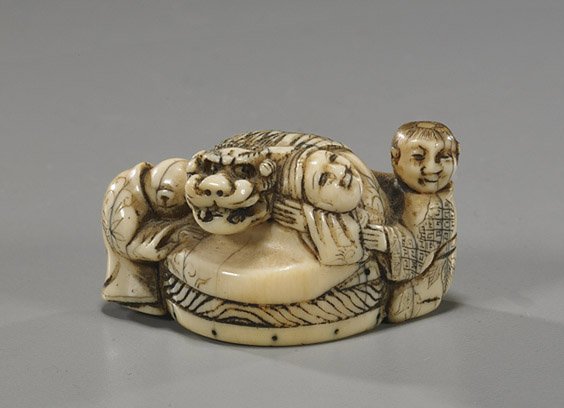 Antique Ivory Netsuke: Figures & Shi-shi: Antique Ivory Netsuke: Figures & Shi-shi Fine and antique carved ivory netsuke; of three figures surrounding an oversized drum with a Shi-shi seated on top, one boy crawling into the drum (some old cr
