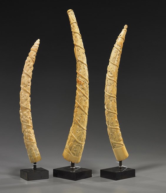 Three Old African Carved Ivory Tusks: Three Old African Carved Ivory Tusks Group of 3 old African carved ivory tusks: one with a nude female to the tip; one with shell form tip; all three with relief carved spiraling scene of figures, ani
