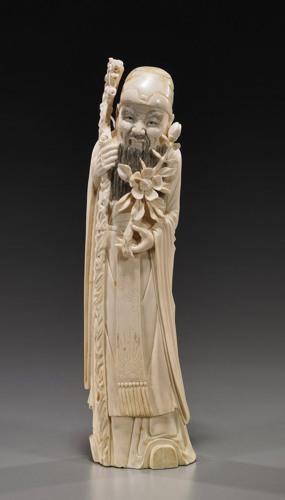 Chinese Carved Ivory Bearded Figure: Chinese Carved Ivory Bearded FigureChinese carved ivory figure of a bearded man; standing in long robes and a cap, holding a staff in one hand, a flowering branch in the other, some gilt remaining on