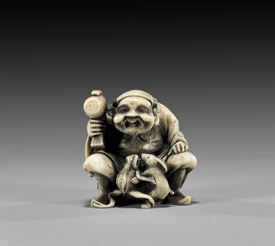 CARVED IVORY NETSUKE: Seated Daikoku: 象牙根付 CARVED IVORY NETSUKE: Seated Daikoku Early 20th Century carved ivory netsuke; of a seated Daikoku with mallet, watching a frog and rabbit wrestling, signed Ikkosai(?) 