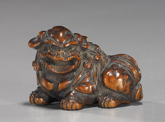 Antique Carved Wood Netsuke: Shi-shi: Antique Carved Wood Netsuke: Shi-shi Antique carved wood netsuke; of a seated shi-shi baring its teeth (old loss to lower jaw and old crack), early 20th Century
