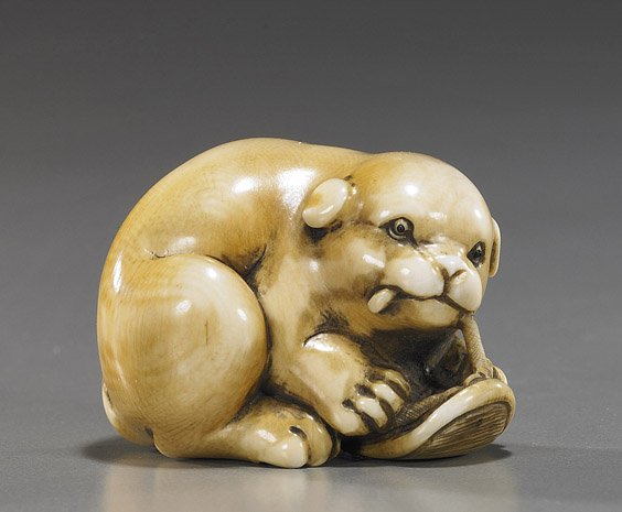 Carved Ivory Netsuke: Puppy with Sandal: Carved Ivory Netsuke: Puppy with Sandal Amusing carved ivory netsuke; of a puppy playing with a small sandal, inlaid eyes, in the manner of Kangyoku, but signed Gyoku