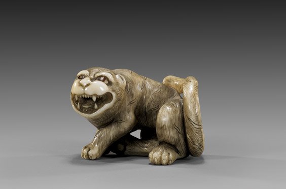 CARVED IVORY NETSUKE: Tiger: 象牙根付 CARVED IVORY NETSUKE: Tiger Scrimmed and carved ivory netsuke; of a snarling tiger, double-inlaid eyes, signed; wood box
