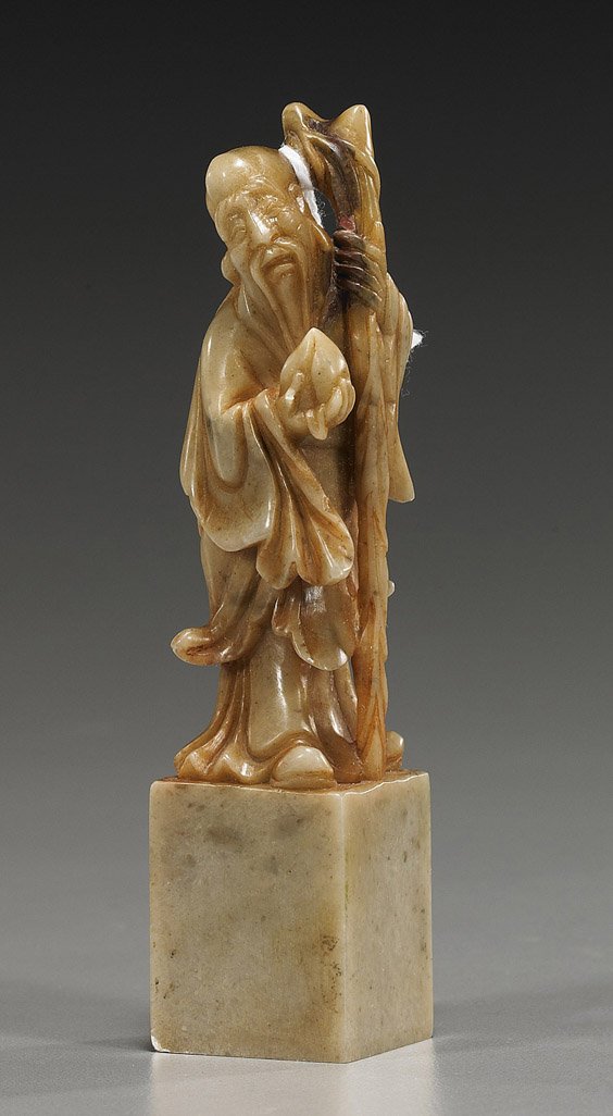 Chinese Carved Soapstone Seal: Chinese Carved Soapstone Figural Seal Chinese carved soapstone seal; surmounted by a figure of Shoulao standing and holding a staff, carrying a peach in his right hand; H: 4 1/4"