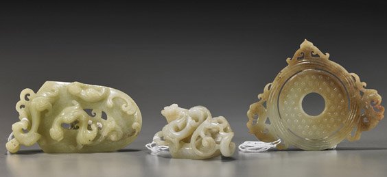 Three Chinese Archaistic Carved Jades: Three Chinese Archaistic Carved Jades Three Chinese archaistic carved jades: yellow openwork shield-form plaque with writhing hydras; beige and tan bi with nipple bosses and openwork border; and celad