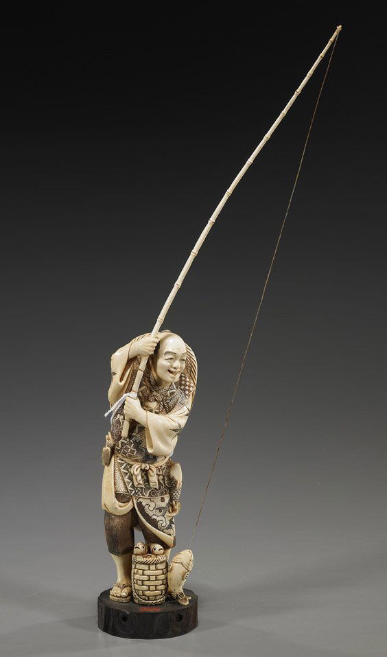 Carved Ivory Okimono: Standing Fisherman: Carved Ivory Okimono: Standing FishermanCarved ivory okimono of a fisherman: standing as he catches a fish on a long bamboo pole; several fish in a basket at his feet and a wide-brimmed hat on his bac
