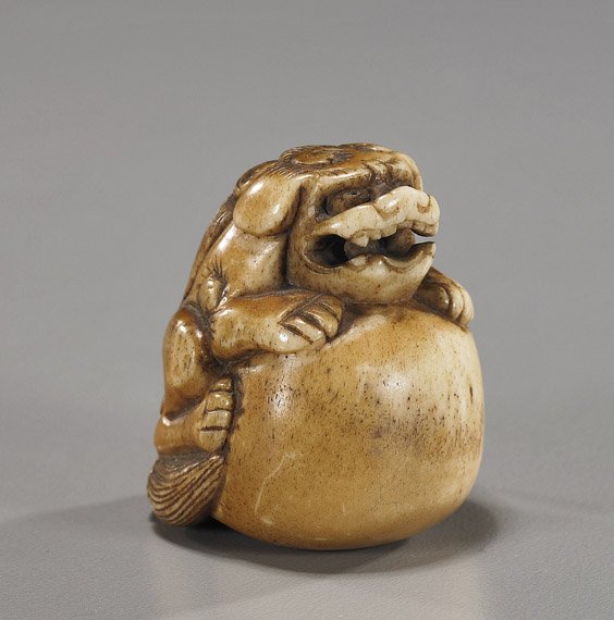Early Carved Bone/Antler Netsuke: Shi-shi: Early Carved Bone/Antler Netsuke: Shi-shi Early carved bone or stag antler netsuke; of a Shi-shi resting its front paws on a large ball, and with a loose ball in its mouth finely patinated (wear), lat