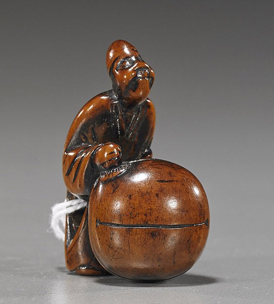 Antique Wood Netsuke: Figure with Mokugyo: Antique Wood Netsuke: Figure with Mokugyo Antique carved wood netsuke; of a figure standing behind a large mokugyo bell (some wear), late 18th/early 19th Century