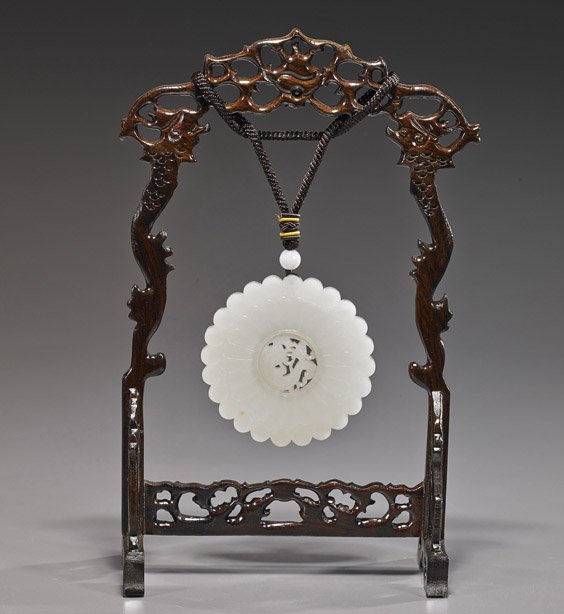 Chinese Carved White Jade Prayer Wheel: Chinese Carved White Jade Prayer Wheel Chinese carved white jade prayer wheel; flora form with rotating central catfish and ruyi fungus medallion; D: 3", carved wood hanging stand with openwork detail