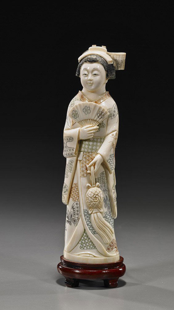 Carved Ivory Okimono: Beauty with Fan: Carved Ivory Okimono: Beauty with FanCarved and lightly polychrome scrimmed ivory okimono; of a beauty standing in butterfly patterned robes and carrying a fan in one hand a foliate lantern in the oth