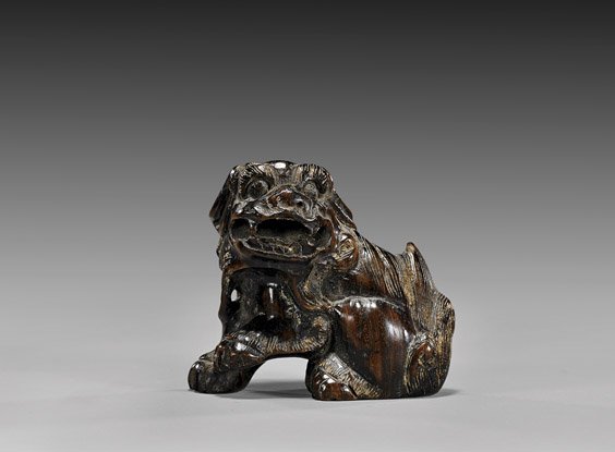 ANTIQUE WOOD NETSUKE: Shi-shi: 木製根付 ANTIQUE WOOD NETSUKE: Shi-shi Antique carved wood netsuke; of a Shi-shi, with one paw up; signed, 19th Century