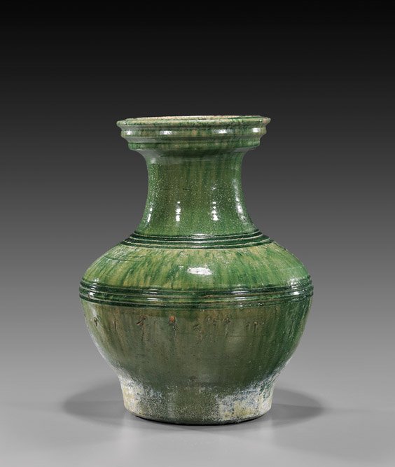 HAN DYNASTY GREEN GLAZED POTTERY HU: 漢 綠釉弦紋瓶 HAN DYNASTY GREEN GLAZED POTTERY HU Large Chinese Han Dynasty, archaic pottery (hu) baluster form vase; with ribbed bands, the 'watermelon-green' glaz