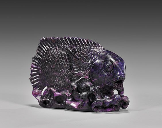 SUGILITE PREDATORY FISH CARVING: 舒俱萊石雕魚 SUGILITE PREDATORY FISH CARVINGArtist: Ronald StevensCarved from deep purple sugilite, this predatory fish has been carved 'swimming' amongst the sea p