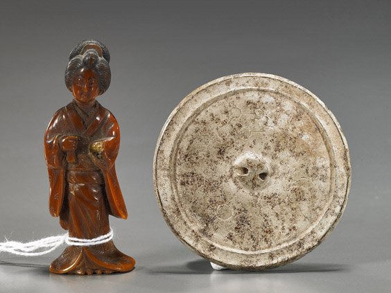 Two Items: Hardstone Mirror & Netsuke: Two Items: Hardstone Mirror & Netsuke Chinese carved hardstone miniature mirror ("calcified"); together with a carved amber-like composite netsuke of a beauty (missing hand); H: 3" (taller)