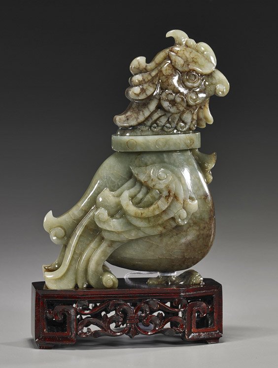 Chinese Carved Jade Bird-Form Vessel: Chinese Carved Jade Bird-Form Vessel Chinese carved jade bird-form vessel and cover: with stylized wings and one claw foot, fine details; green with brown suffusions; H: 7", wood stand