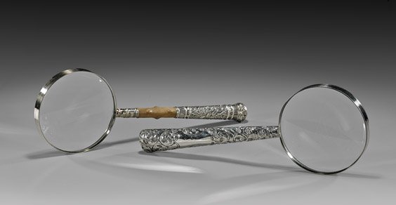 TWO ANTIQUE MAGNIFYING GLASSES: 鍍銀柄放大鏡 兩件 TWO ANTIQUE MAGNIFYING GLASSES Two antique magnifying glasses: the shorter with English repoussé silver handle of scrolling foliage m