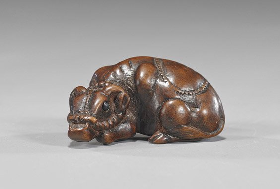 Antique Carved Wood Netsuke: Ox: Antique Carved Wood Netsuke: Ox Antique carved wood netsuke; of a recumbent ox with lead ropes, inlaid eyes, inscribed signature Tomotada (wear), 19th Century