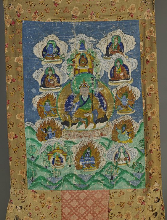 Tibetan Buddhist Thanka: Various Deities: Tibetan Buddhist Thanka: Various Deities Silk mounted Tibetan thanka; depicting a central deity wearing long robes and cap, seated on a lotus pedestal and holding ritual objects, surrounded by other d