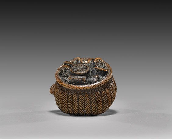ANTIQUE CARVED WOOD NETSUKE: Basket: 木製根付 ANTIQUE CARVED WOOD NETSUKE: Basket Antique carved wood netsuke; of a basket, the removable lid with logs in relief; late 19th Century, possibly for use as a smoker's 