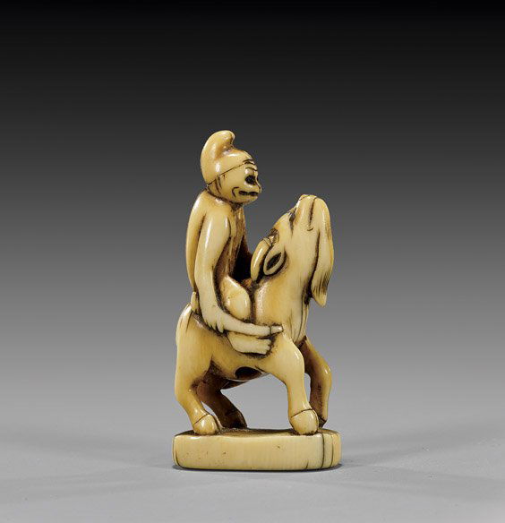 ANTIQUE CARVED IVORY NETSUKE: Monkey & Goat: 象牙根付 ANTIQUE IVORY NETSUKE: Monkey & GoatAntique and charming, carved ivory netsuke; of a monkey wearing a hat, riding on a goat, with inlaid eyes and finely patinated, uns