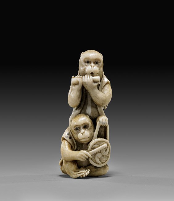 CARVED IVORY NETSUKE: Monkeys: 象牙根付 CARVED IVORY NETSUKE: Two Monkeys Carved ivory netsuke; of two monkeys, one standing and playing a flute, the other seated in front with a drum; with inlaid eyes and i