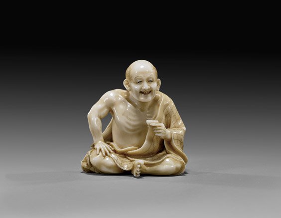 CARVED IVORY NETSUKE: Monk: 象牙根付 CARVED IVORY NETSUKE: Seated Monk Carved ivory netsuke; of a jolly seated monk holding a cup of sake, early 20th Century, signed on inlaid lacquered reserve; Provenanc