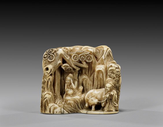 ANTIQUE CARVED IVORY NETSUKE: 象牙根付 ANTIQUE IVORY NETSUKE: Mountains Antique carved ivory netsuke; in the form of a miniature mountain-like range, protecting a little clearing of figures and an ox beneat