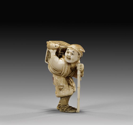CARVED IVORY NETSUKE: Traveler: 象牙根付 CARVED IVORY NETSUKE: Traveling Man Early 20th Century, carved ivory netsuke; of a traveling man with bamboo walking stick, carrying a bird in his hand, and with a box