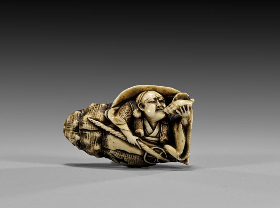 ANTIQUE IVORY NETSUKE: Man in Shell: 象牙根付 ANTIQUE IVORY NETSUKE: Man in Shell Finely detailed, antique ivory netsuke: of a figure within a conch shell blowing a conch shell horn; unsigned; late 19th Century