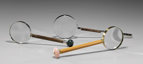 THREE VARIOUS MAGNIFYING GLASSES: 各異放大鏡 三件 THREE VARIOUS MAGNIFYING GLASSES Three early 20th Century magnifying glasses: the longest with wood and Sterling silver handle set with facete