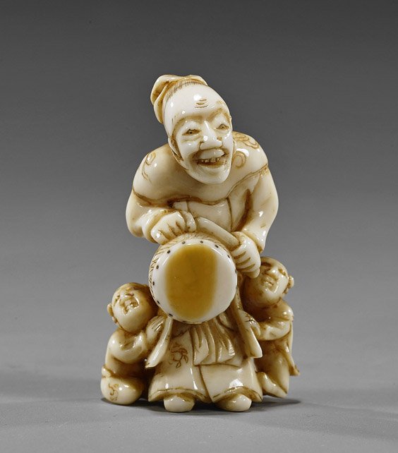 Antique Carved Ivory Netsuke: Drum: Antique Carved Ivory Netsuke: Drum Antique carved ivory netsuke; of a standing figure with drum and 2 karako at his feet, finely patinated, late 19th Century
