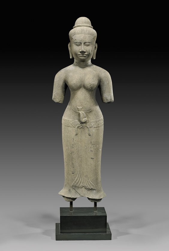 CAMBODIAN CARVED SANDSTONE FIGURE: CAMBODIAN CARVED SANDSTONE FIGURE Cambodian carved sandstone figure; the well formed parcel-nude with hair in a stylized top knot, and wearing a pleated skirt with details in relief; with typical loss