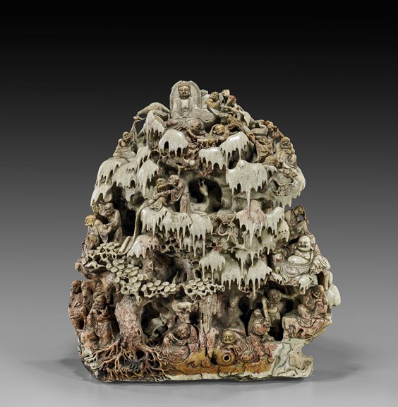 CARVED SOAPSTONE LOHAN GROUP: CHINESE CARVED SOAPSTONE LOHAN GROUP Large Chinese carved soapstone group; depicting the Eighteen Lohans with attendants, all in various positions within a grotto-like mountain amid rockery and pine b