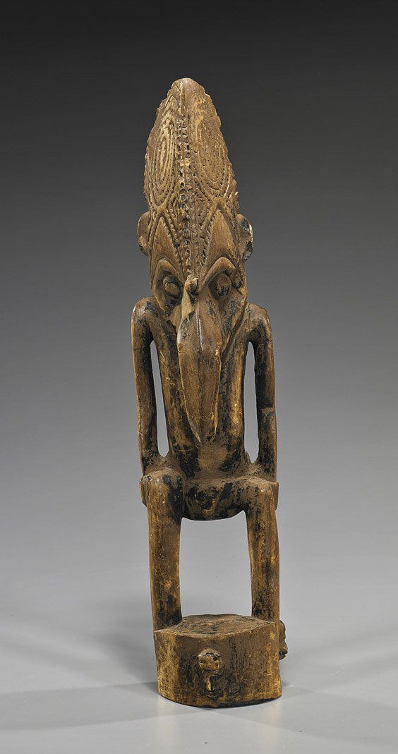 Tall Old New Guinea Carved Wood Figure: Tall Old New Guinea Carved Wood FigureTall and old, New Guinea carved wood figure of a male; standing on a circular plinth and wearing a mask with beak-like nose (considerable wear and crack); H: 23"