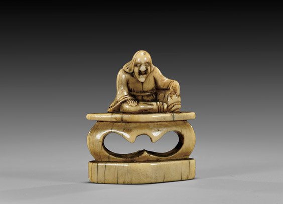 ANTIQUE IVORY SEAL-TYPE NETSUKE: ANTIQUE IVORY SEAL-TYPE NETSUKE Antique carved ivory seal-type netsuke; of a sage seated atop a pedestal stand, displaying fine patination, 18th Century; unsigned 象牙根付