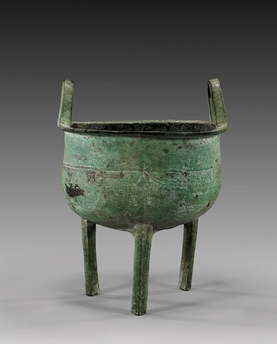 ARCHAIC CHINESE BRONZE VESSEL: ARCHAIC CHINESE BRONZE VESSEL Archaic Chinese, Warring States/Han Dynasty bronze tripod vessel (ding); the simple bowl-form set on three tall slim legs, with two upright loop handles; of very attracti