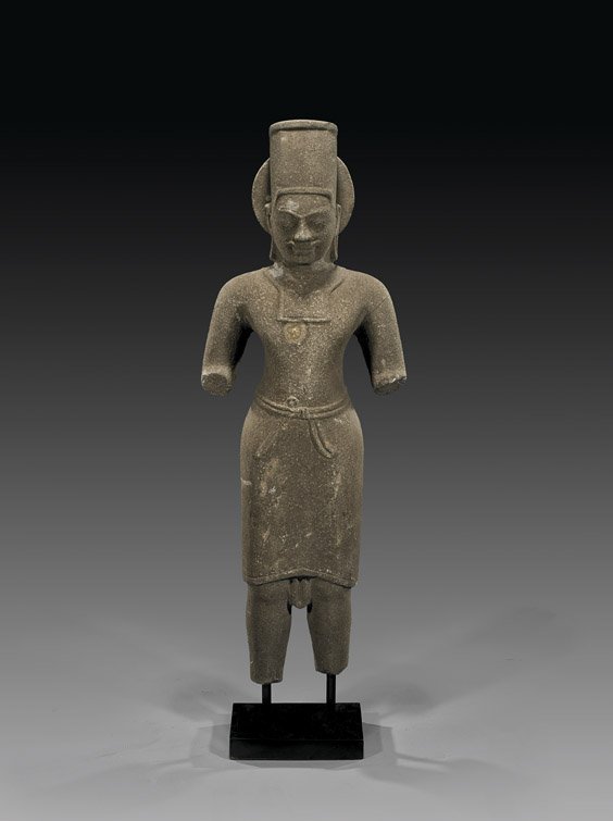CAMBODIAN CARVED STONE DEITY FIGURE: CAMBODIAN CARVED STONE DEITY FIGURECambodian carved stone figure (possibly Khmer, Circa 7th Century), of the Sun god Surya, standing in stylized strong stance with broad shoulders; a round mandorla be
