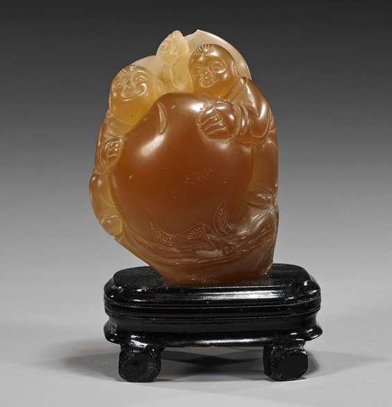 Chinese Carved Soapstone/Sealstone Group: Chinese Carved Soapstone/Sealstone Group Chinese carved soapstone or sealstone group; depicting the He-he twins with a large peach, transparent coffee color (chip to one head); H: 4", wood stand
