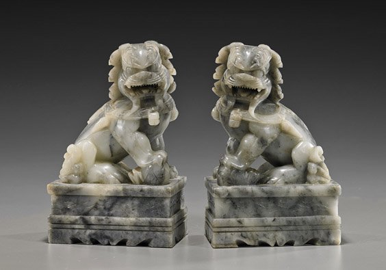 Pair Chinese Carved Soapstone Seated Lions: Pair Chinese Carved Soapstone Seated Lions Pair Chinese carved soapstone lions; each seated atop a decorative pedestal for use as bookends: one with ball, the other with a cub, both baring their teeth