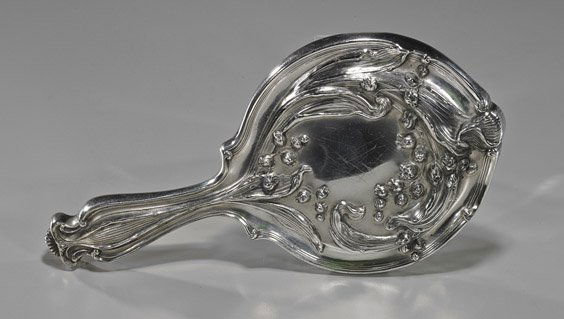Antique Art Nouveau Design Hand Mirror: Antique Art Nouveau Design Hand MirrorElaborate antique Art Nouveau silver-plated hand mirror; with design of lily of the valley florals and foliage to the back, the mirror bezeled (small flaws), Circ
