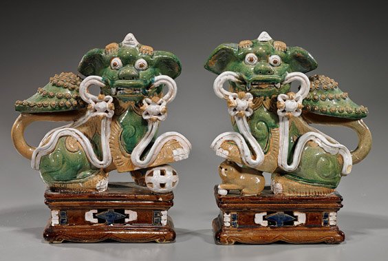 Pair Colorful Glazed Asian Pottery Lions: Pair Colorful Glazed Asian Pottery Lions Pair Southeast Asian or South China, colorful glazed pottery lions; each standing atop a decorative rectangular plinth and both holding a sash in their mouths: