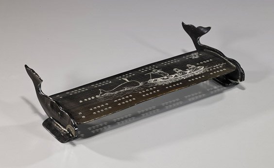 Old Eskimo Scrimmed Baleen Cribbage Board: Old Eskimo Scrimmed Baleen Cribbage Board Rare old Eskimo scrimmed baleen cribbage board; rectangular with whale-form stand to each end and with whaling scene, signed Betty Hughey; L: 12"